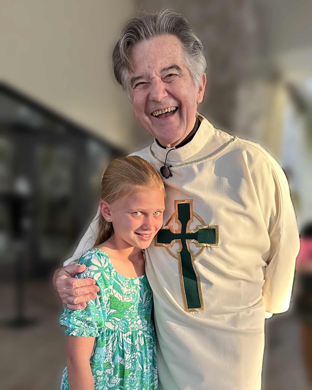 Fr. Danny Murphy laughing outside the doors of Holy Cross, his arm around a young parishioner.